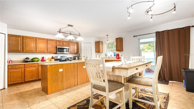 kitchen featuring appliances with stainless steel finishes, pendant lighting, light tile patterned floors, and track lighting