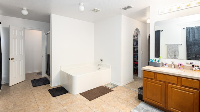 bathroom featuring independent shower and bath, vanity, a textured ceiling, and tile patterned flooring