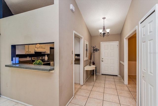 tiled entrance foyer with a notable chandelier, vaulted ceiling, and a textured ceiling