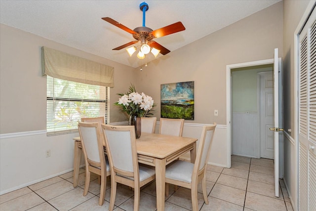 tiled dining area with a textured ceiling and ceiling fan