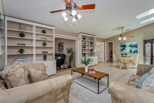 tiled living room with a textured ceiling, lofted ceiling with skylight, and ceiling fan