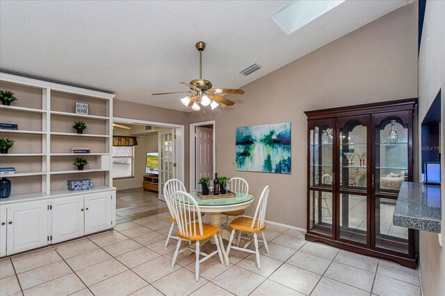 tiled dining space featuring a textured ceiling, vaulted ceiling with skylight, and ceiling fan