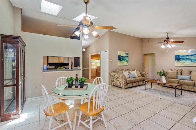 tiled dining area with high vaulted ceiling, a skylight, and ceiling fan