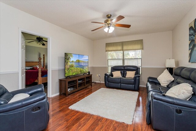 living room featuring ceiling fan, a textured ceiling, and dark wood-type flooring