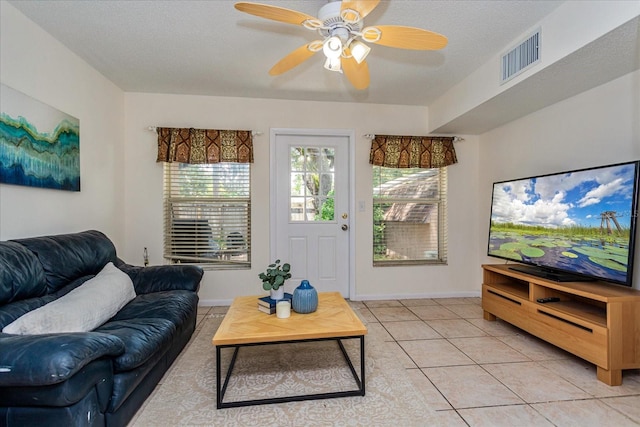 tiled living room with a textured ceiling and ceiling fan