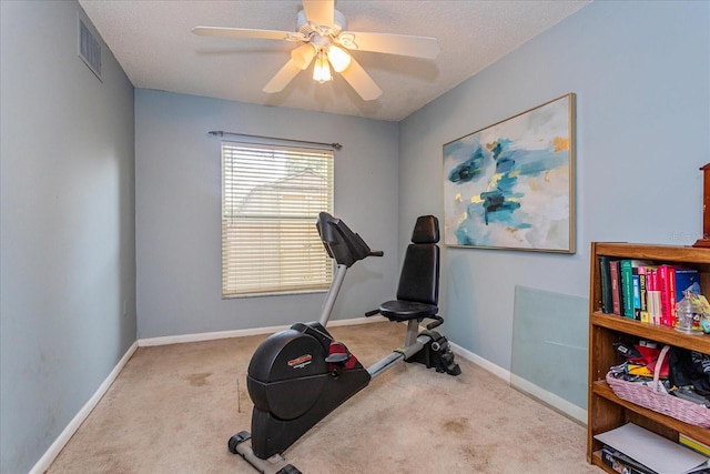 exercise area with ceiling fan, light colored carpet, and a textured ceiling