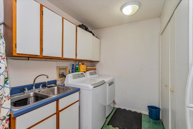 laundry room with washing machine and clothes dryer, a textured ceiling, cabinets, and sink