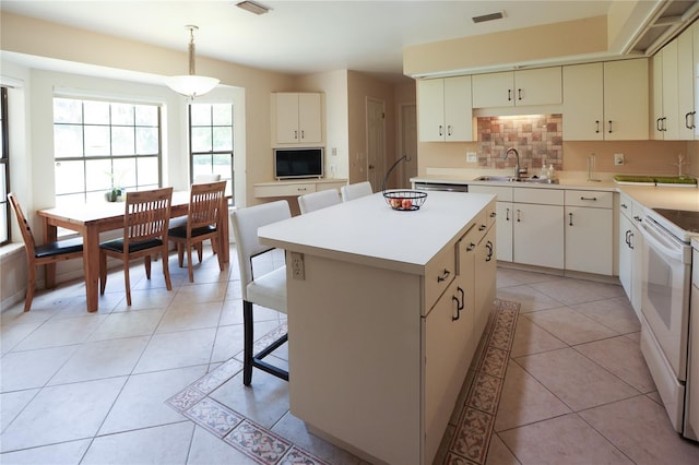 kitchen featuring backsplash, sink, electric stove, light tile patterned floors, and a center island