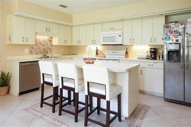 kitchen with sink, a kitchen bar, appliances with stainless steel finishes, and a kitchen island