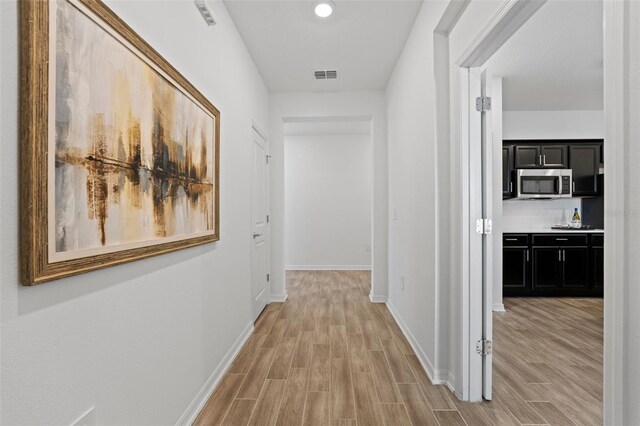 hallway featuring baseboards, visible vents, and light wood-style floors