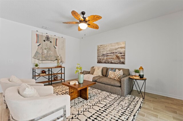 living room featuring visible vents, ceiling fan, baseboards, and wood finished floors