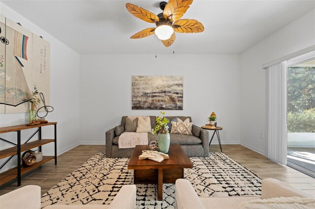 living area featuring a ceiling fan, light wood-type flooring, and baseboards