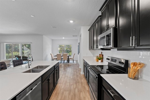 kitchen featuring visible vents, appliances with stainless steel finishes, dark cabinets, light countertops, and a sink