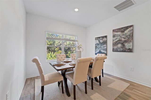 dining area featuring visible vents, light wood-style flooring, and baseboards