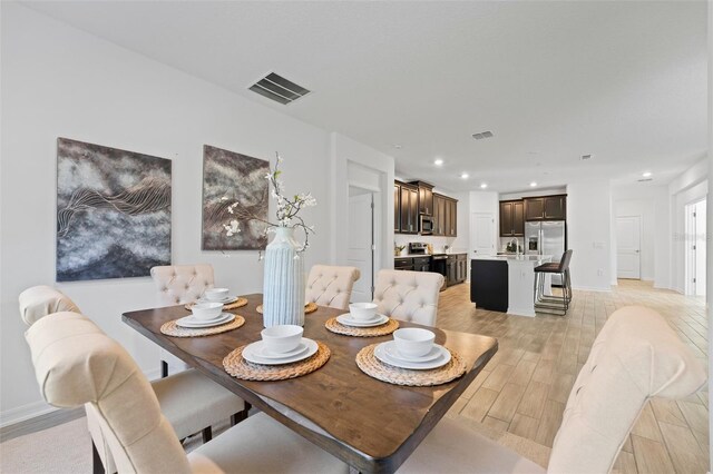 dining room with light wood-type flooring, visible vents, baseboards, and recessed lighting