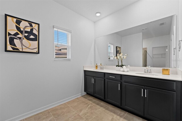 bathroom with double vanity, a sink, visible vents, and baseboards