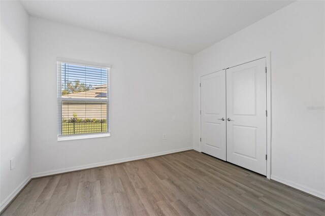 unfurnished bedroom with a closet, baseboards, and wood finished floors