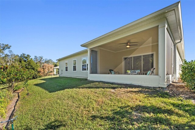 rear view of property with ceiling fan, a yard, and a sunroom