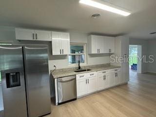 kitchen with appliances with stainless steel finishes, sink, light hardwood / wood-style flooring, and white cabinets