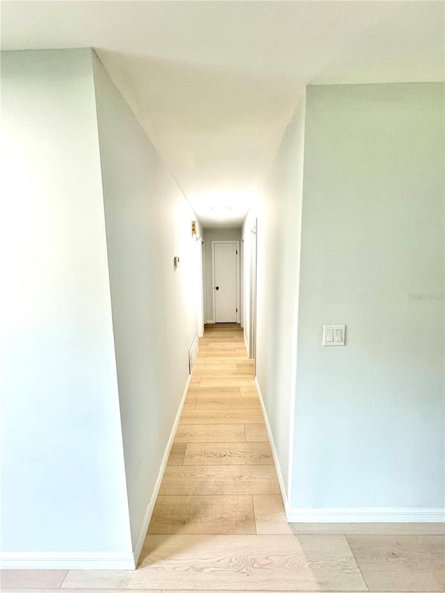 corridor featuring light wood-style floors, visible vents, and baseboards