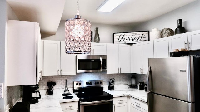 kitchen featuring backsplash, white cabinets, vaulted ceiling, light stone counters, and stainless steel appliances