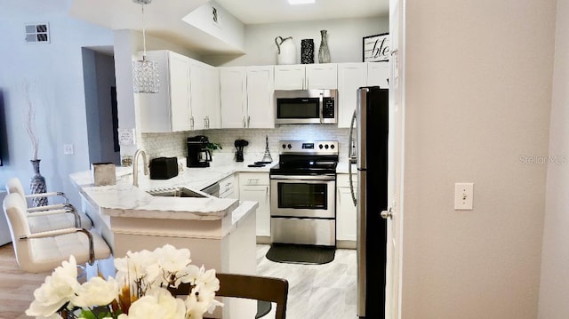 kitchen featuring sink, tasteful backsplash, kitchen peninsula, stainless steel appliances, and white cabinets