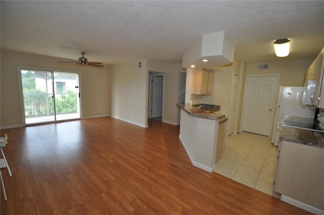 kitchen with visible vents, a textured ceiling, a ceiling fan, and light wood finished floors