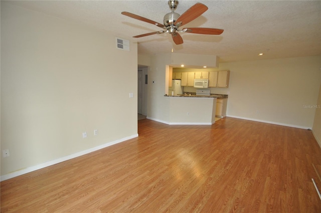 unfurnished living room with ceiling fan, visible vents, baseboards, and light wood-style flooring