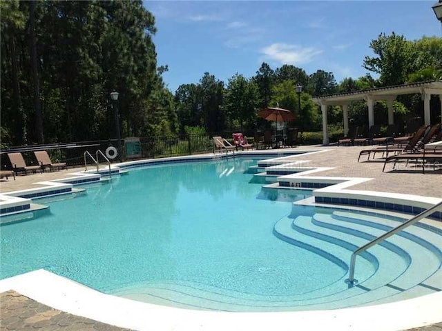 pool with a pergola, a patio area, and fence