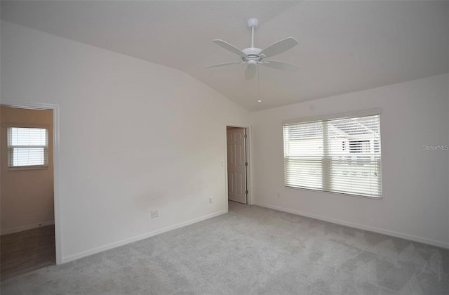 carpeted spare room with a wealth of natural light, ceiling fan, and vaulted ceiling