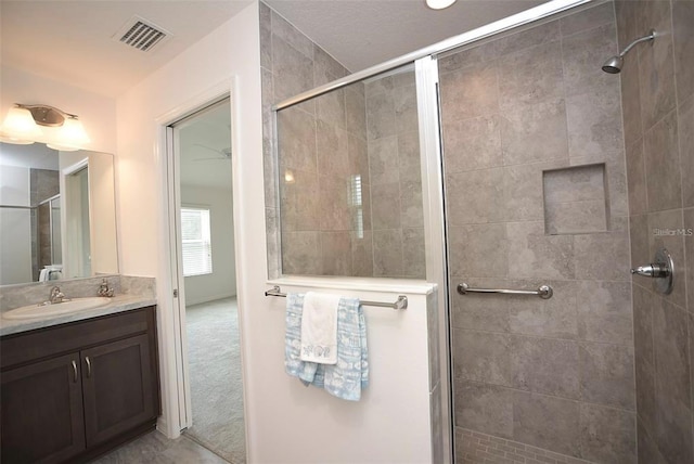 bathroom with tile patterned flooring, a shower with shower door, and vanity