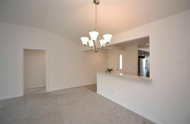 carpeted spare room with an inviting chandelier and lofted ceiling