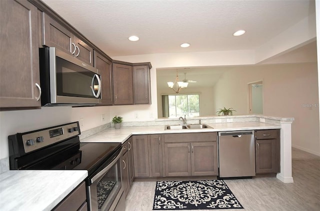 kitchen with kitchen peninsula, stainless steel appliances, light hardwood / wood-style floors, dark brown cabinetry, and sink