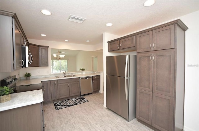 kitchen featuring dark brown cabinets, stainless steel appliances, sink, light hardwood / wood-style floors, and a textured ceiling