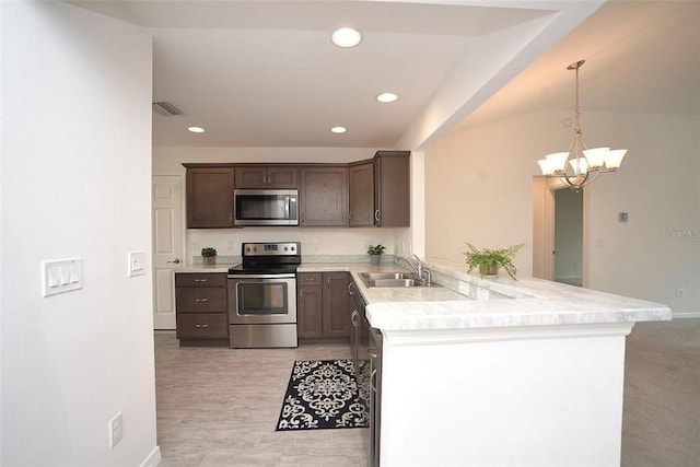 kitchen with stainless steel appliances, sink, kitchen peninsula, decorative light fixtures, and a notable chandelier