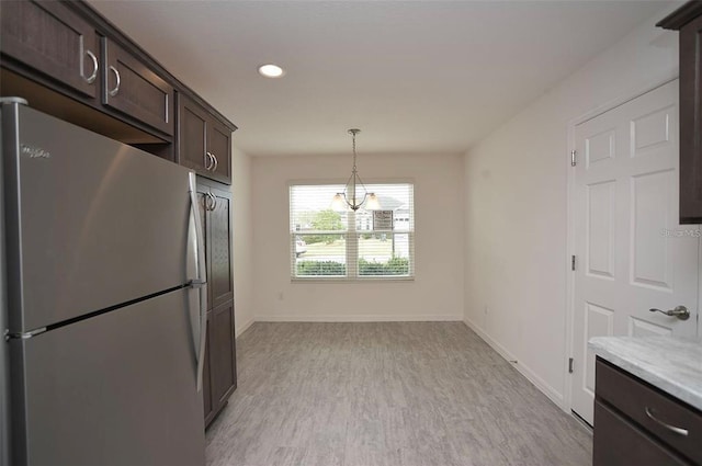 kitchen with white refrigerator, dark brown cabinets, hanging light fixtures, light hardwood / wood-style floors, and a notable chandelier