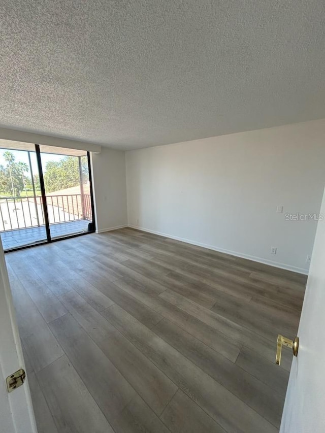spare room with baseboards, wood finished floors, and a textured ceiling
