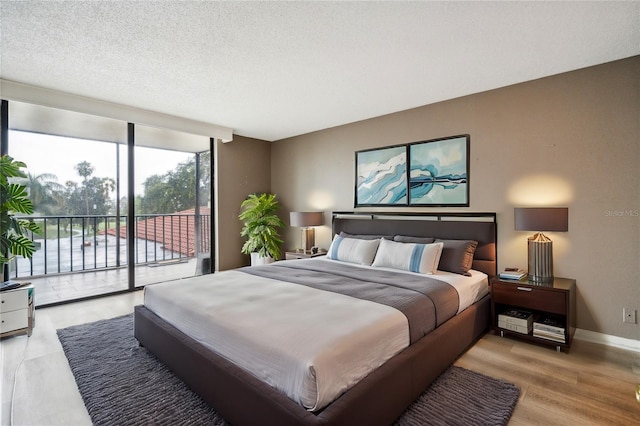 bedroom with a textured ceiling, access to outside, and light hardwood / wood-style flooring