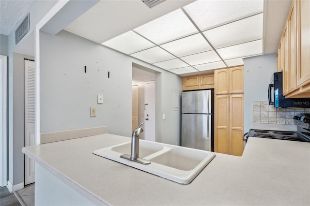 kitchen featuring stainless steel refrigerator, sink, tasteful backsplash, kitchen peninsula, and light brown cabinetry