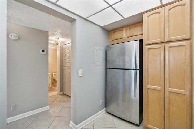 kitchen with stainless steel fridge, light brown cabinets, and light tile patterned flooring