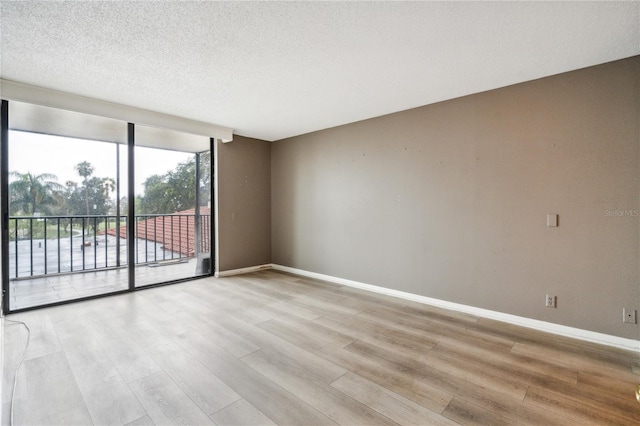 spare room with a textured ceiling and light hardwood / wood-style flooring