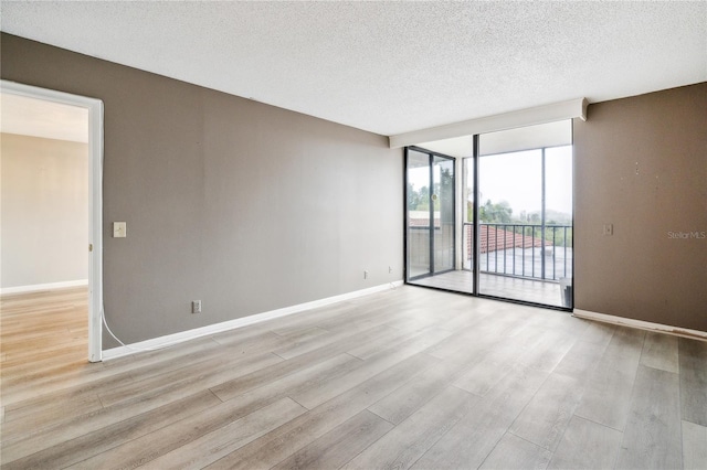 spare room featuring light hardwood / wood-style flooring and a textured ceiling