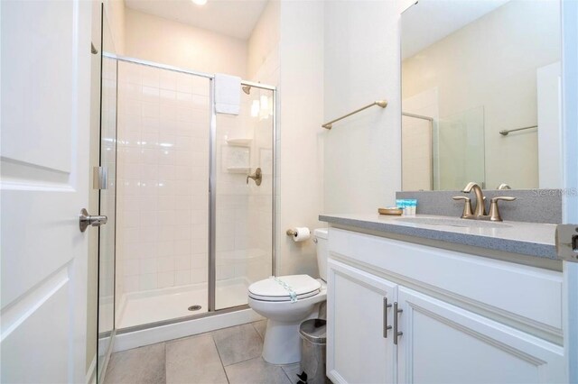 bathroom featuring tile patterned floors, vanity, a shower with shower door, and toilet