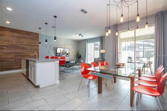 kitchen featuring white cabinets, decorative light fixtures, wood walls, and light tile patterned floors