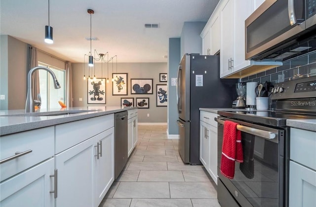 kitchen with stainless steel appliances, sink, hanging light fixtures, decorative backsplash, and white cabinetry