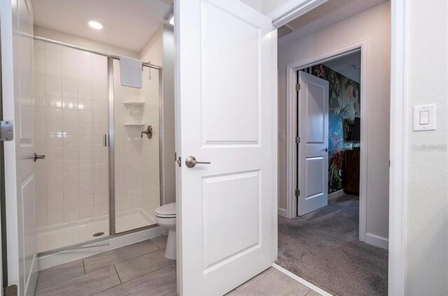 bathroom featuring toilet, tile patterned flooring, and an enclosed shower