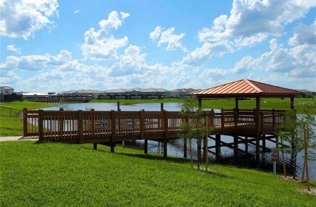 dock area featuring a gazebo, a water view, and a lawn