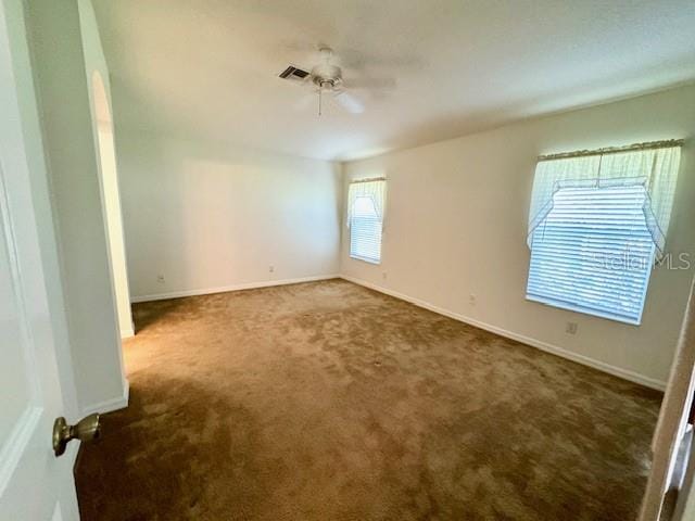 empty room featuring ceiling fan and carpet