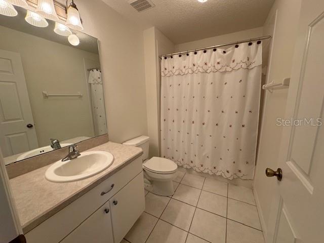 bathroom with tile patterned flooring, toilet, a textured ceiling, and vanity