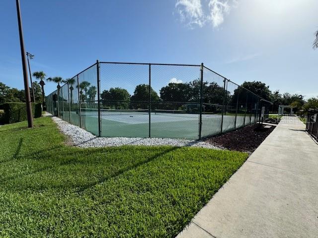 view of tennis court with a yard